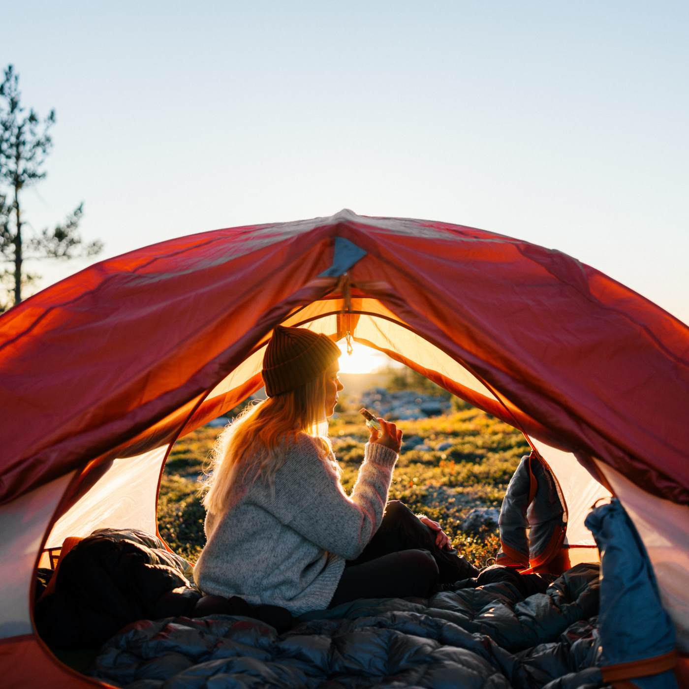 Girl eating a RAWBITE at sunset in a tent