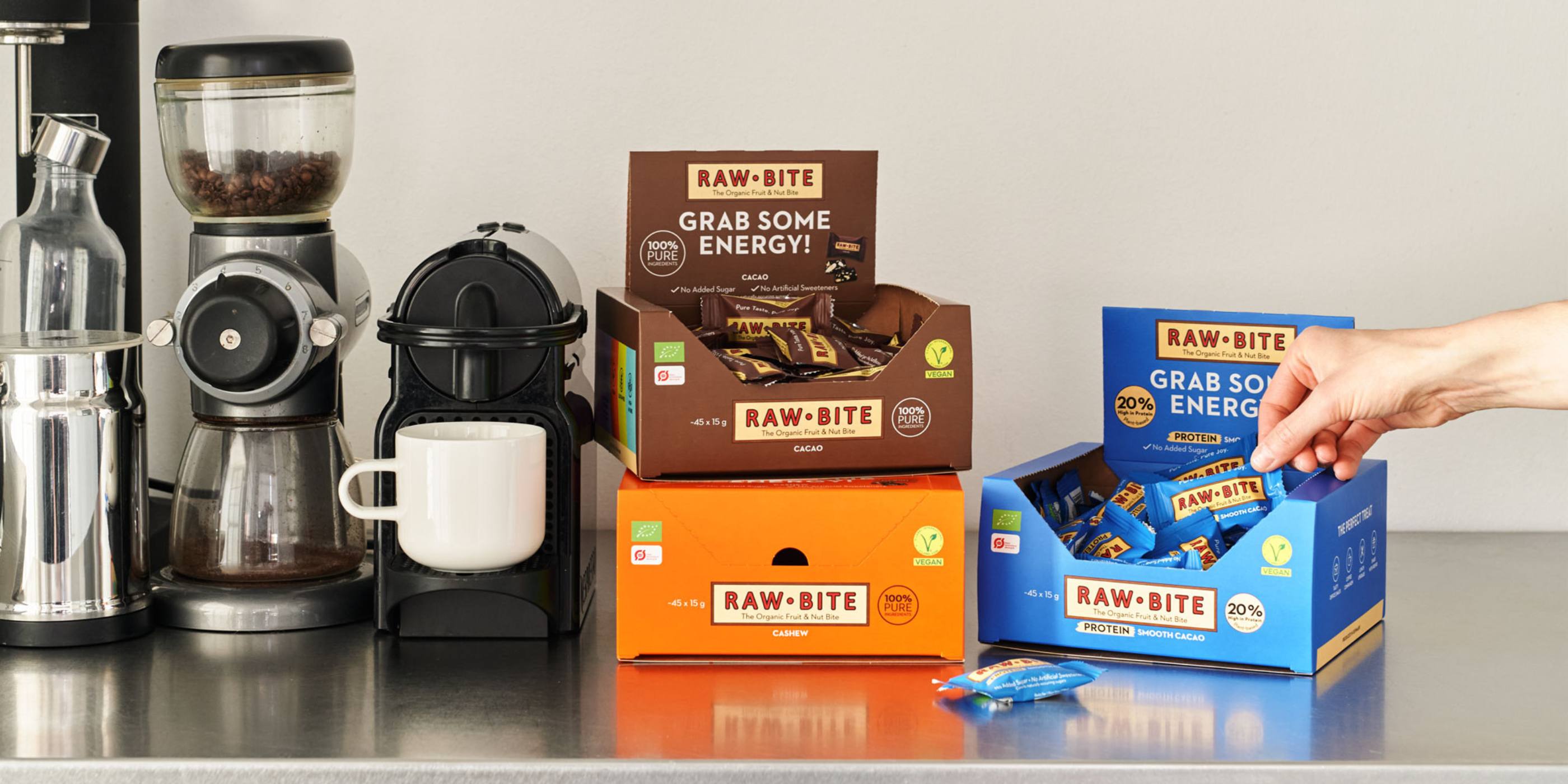 RAWBITE Office Boxes displayed on a counter with coffee-making equipment.