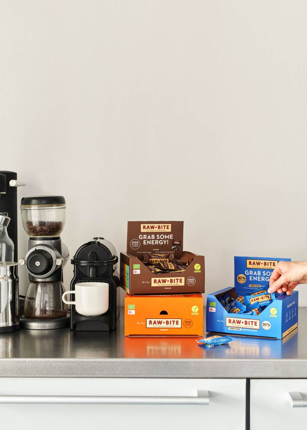 RAWBITE bars on a kitchen counter with coffee-making equipment.