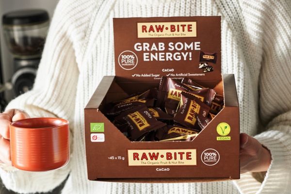 Office Box with Cacao mini bars held by a person with a coffee cup in a cozy setting